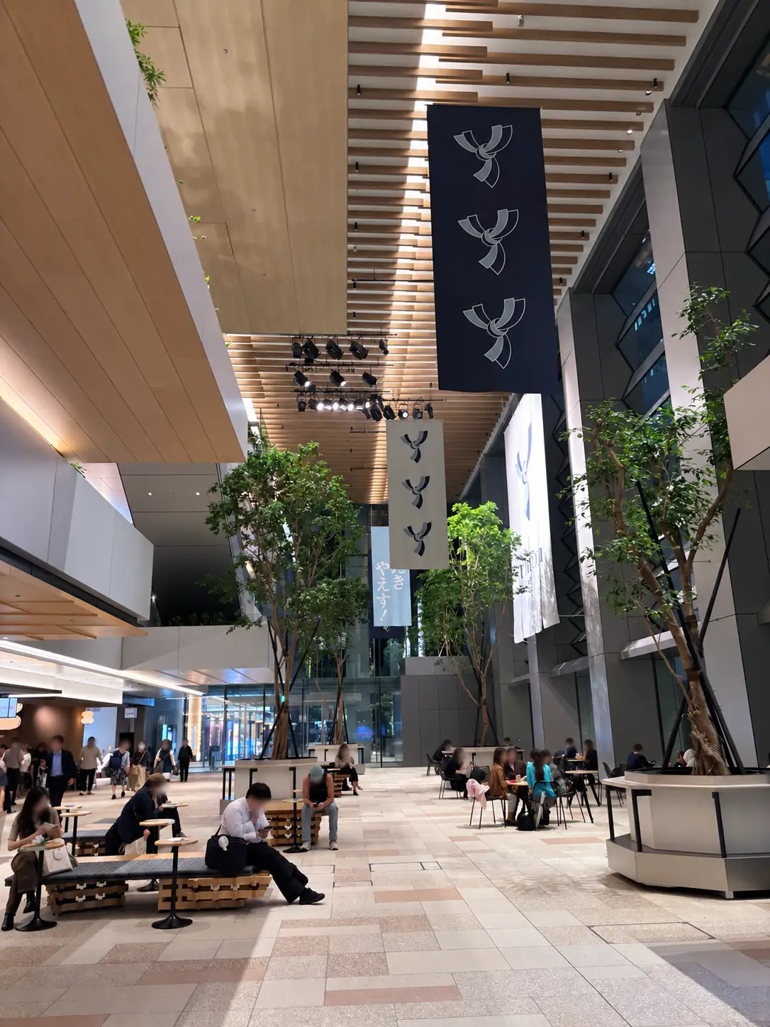 Hinokicho Square interior at TOFROM YAESU with trees, benches, tables and visitors resting