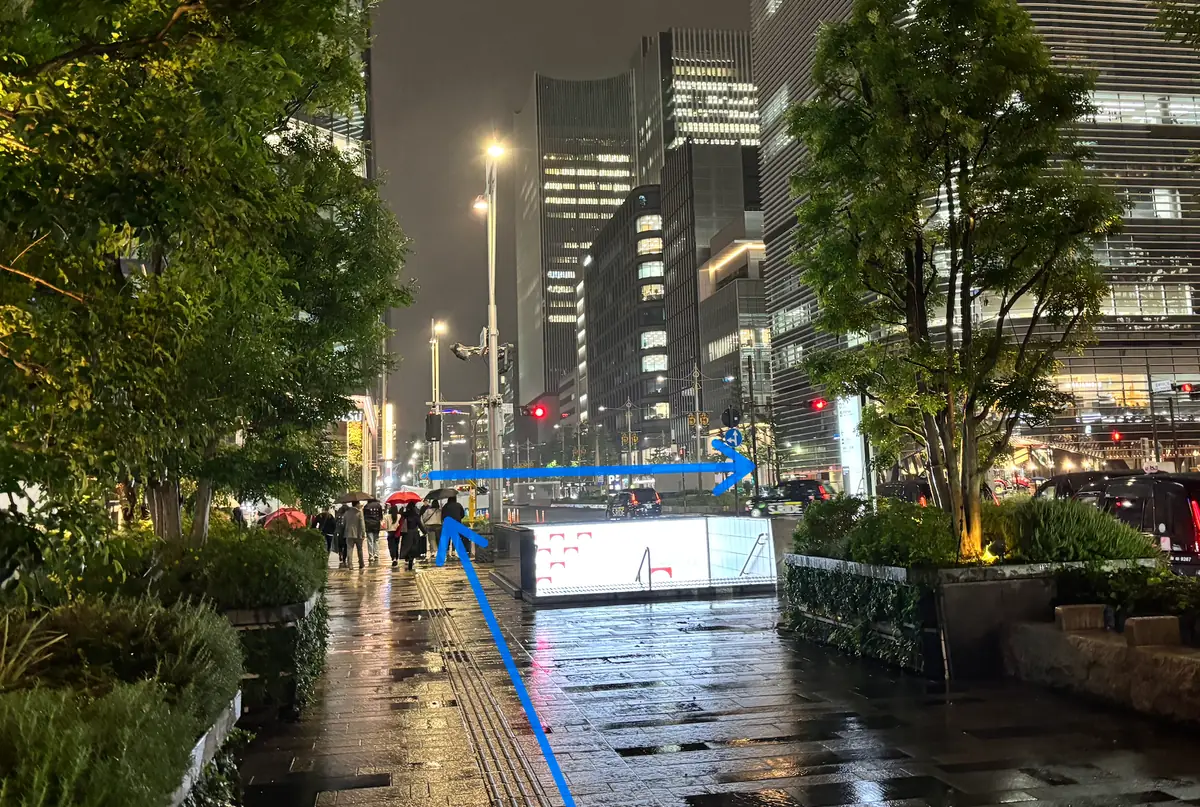 Nighttime pedestrian route from Tokyo Station toward Tokyo Midtown Yaesu with blue arrows showing where to cross and turn right