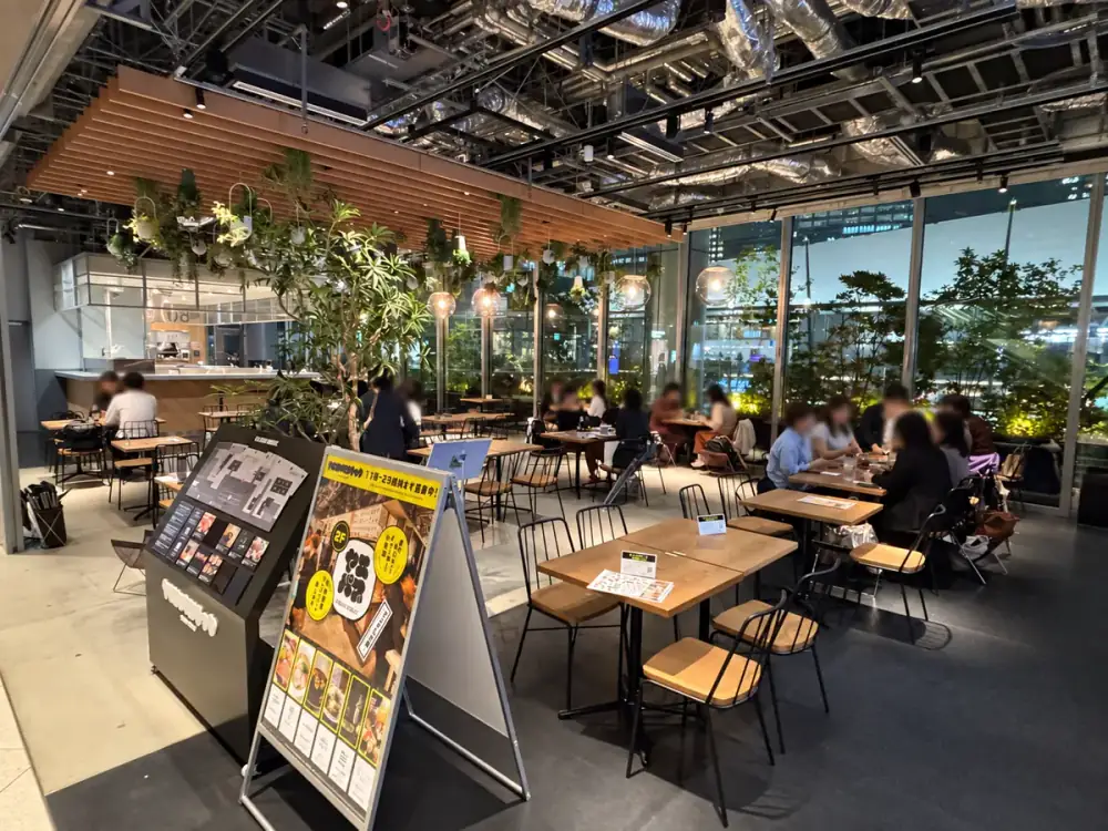 Open shared tables and indoor greenery on the second floor of Tokyo Midtown Yaesu